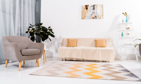 A living room in light colors with a patterned rug.