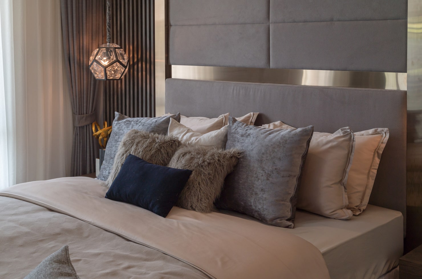 Queen sized bed with multiple throw pillows in different shades of gray, brown and black.